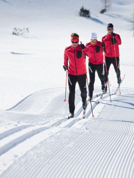 Langlaufen Obertauern Drei Langläufer in roten Jacken auf einer präparierten Schneestrecke